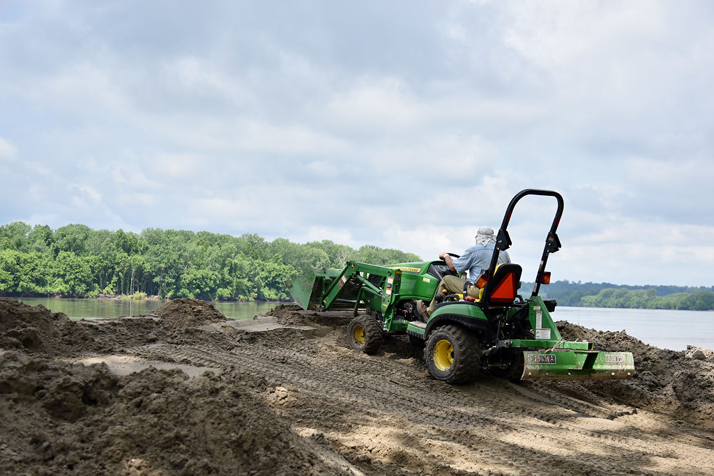 Jonathan Lauten pushes mud and sand away from the campground, toward the river